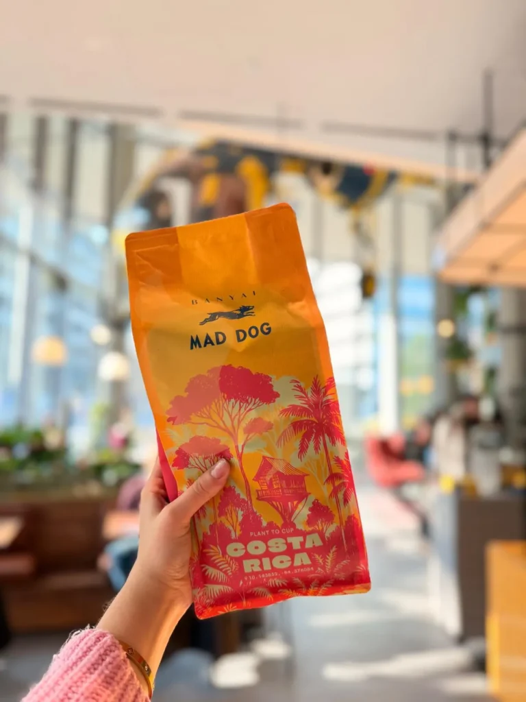 Mad Dog Coffee kávécsomag kézben a kávézó teraszán